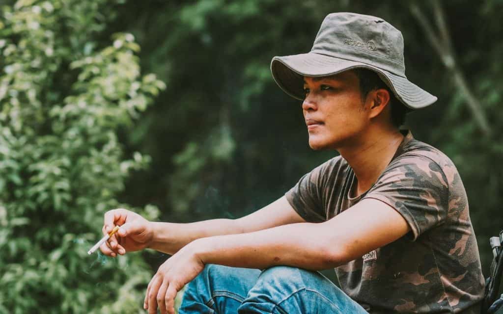 a man holding a cigarette when camping outdoor