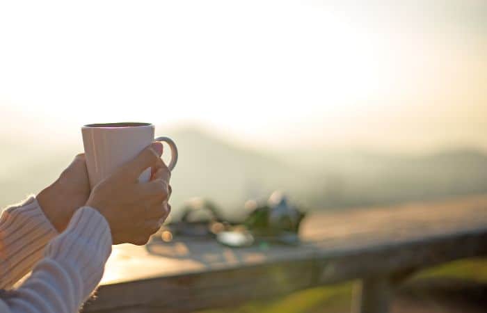 a woman holding coffee cup when camping outdoor