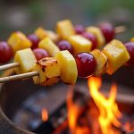 Campfire fruit skewers with pineapple, apples, and grapes, roasted for a delicious outdoor treat.