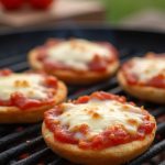 Campfire Mini Pizzas made with English muffins, topped with sauce and cheese, cooking over an open fire.