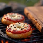 Campfire Pizza Bagels topped with sauce and cheese, grilling over an open fire for a tasty outdoor snack.